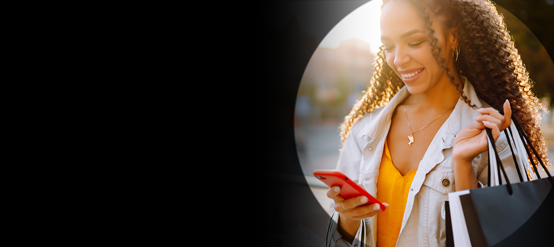 Mujer mirando su teléfono con una bolsa de compras