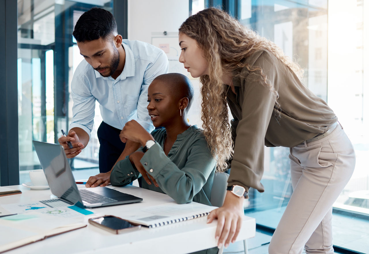 Team members gathered around a laptop with a focus on collaboration.