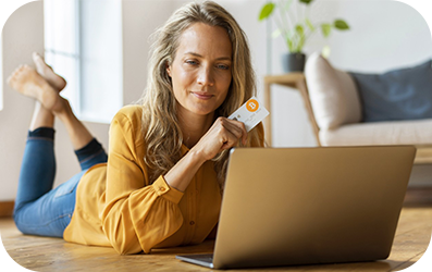 Femeie care ține un card de credit în timp ce se uită la laptop