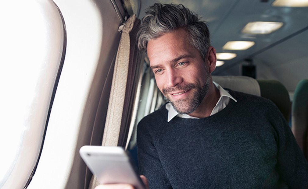 Čovek gleda u telefon dok je u avionu