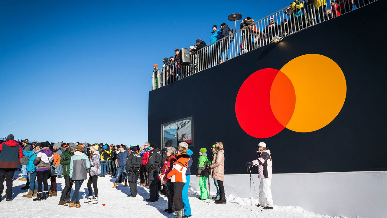 En folkmassa utanför en byggnad med Mastercard-logotypen.