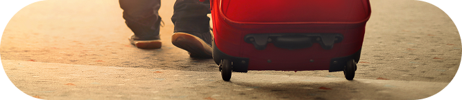 Businessman walking with red suitcase inside airport before work travel.