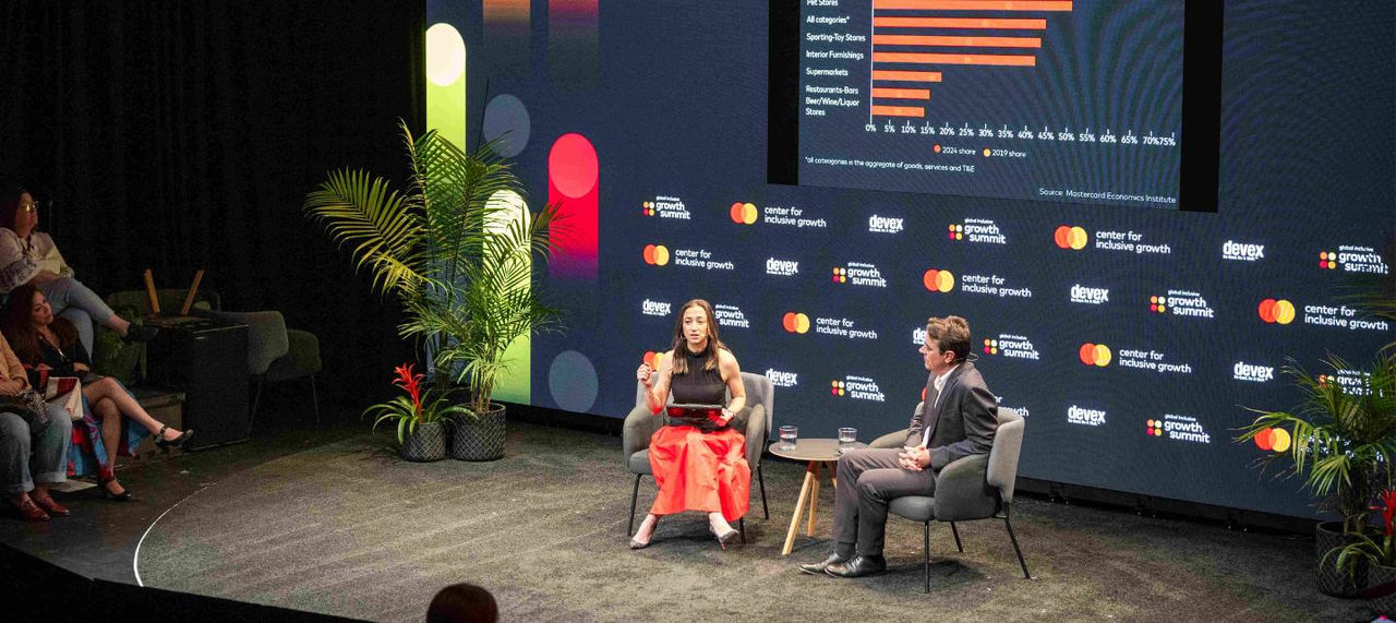 Michelle Meyer and Wolfgang Fengler sit on the stage at GIGS in front of a screen showing an infographic. 