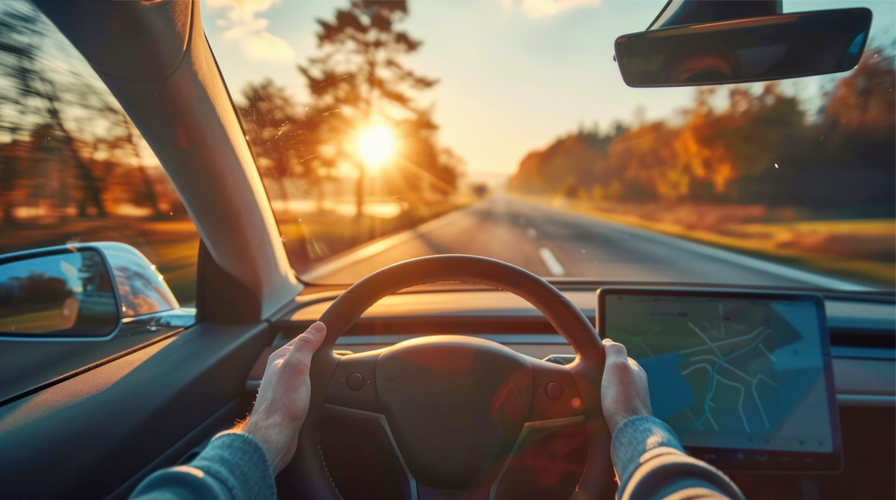 Person driving down a road during a sunset.