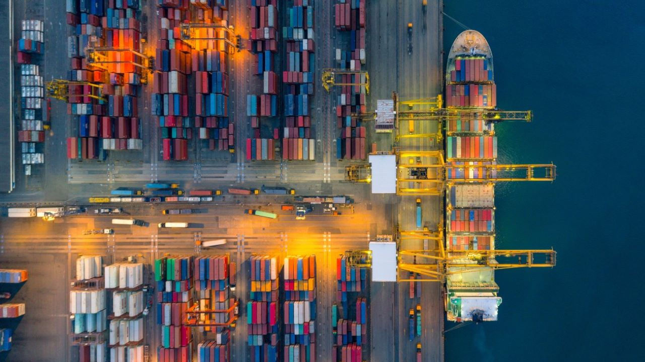 An overhead shot of a cargo ship being loaded at at dock. 