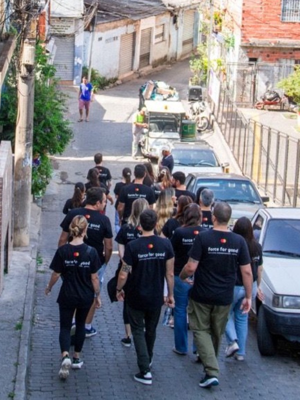 The team of Mastercard volunteers in Force for Good T-shirts walk down a street in the favela. 