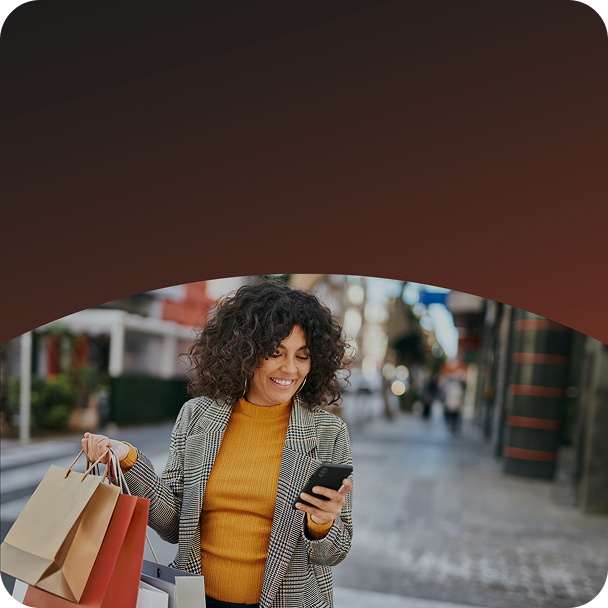 Customer carrying shopping bags looking at smartphone.