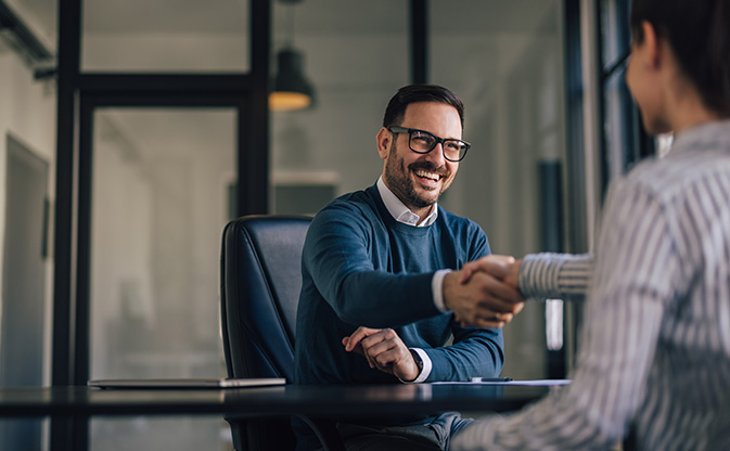 A man shakes hands with a coworker in an office symbolizing a professional agreement or collaboration.