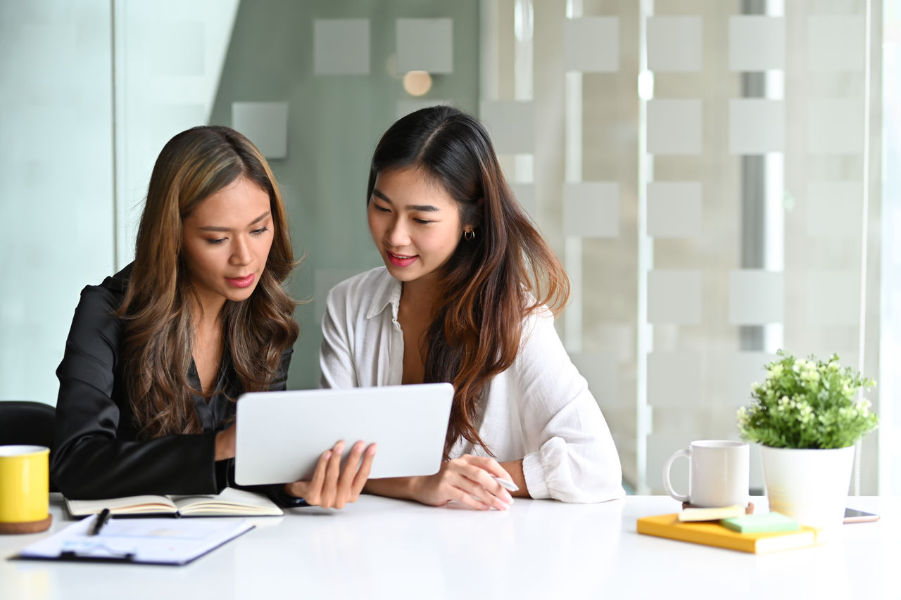 Two women collaborating on tablet device.
