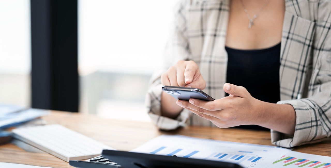 Person using phone while sitting at desk.