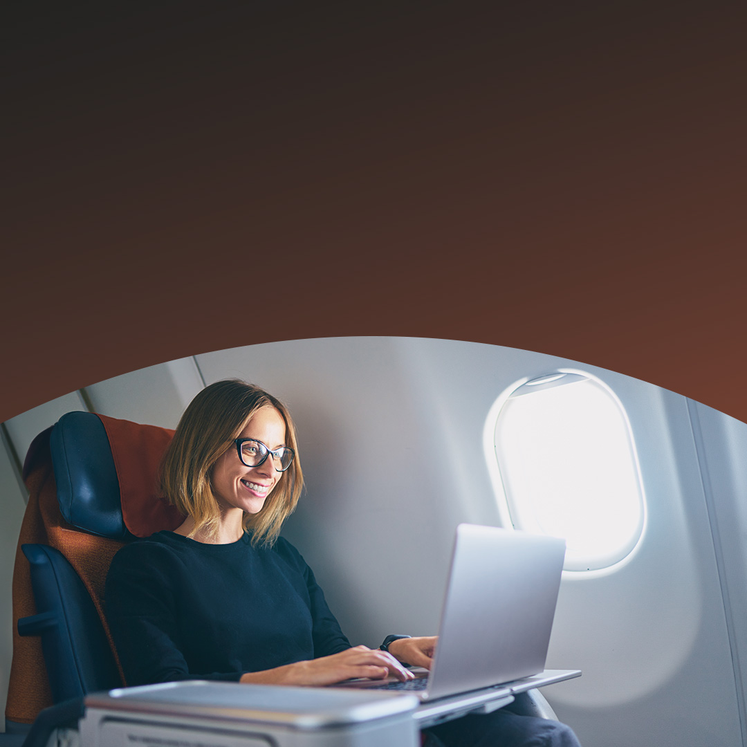 Woman working on her laptop on an airplane. 