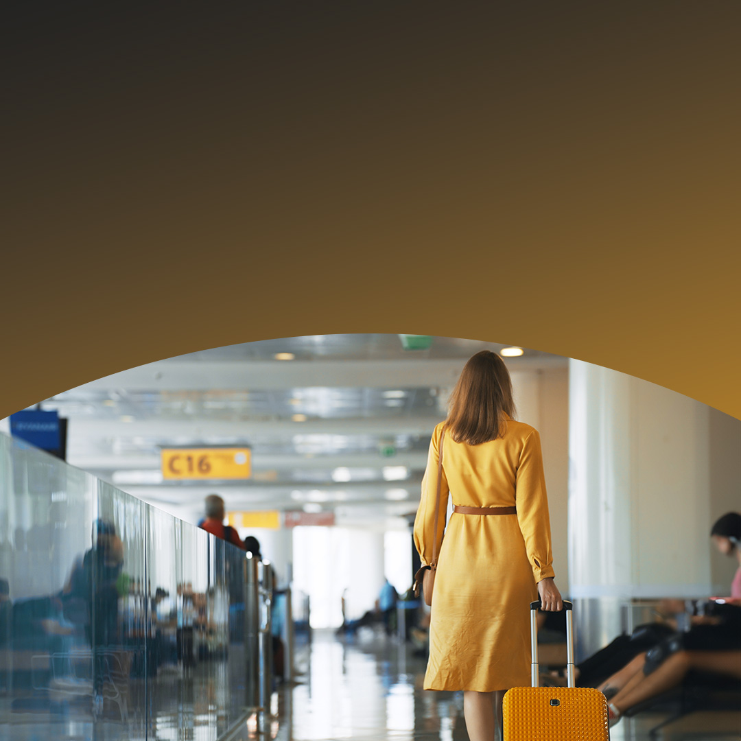 Woman walking through an airport with luggage. 