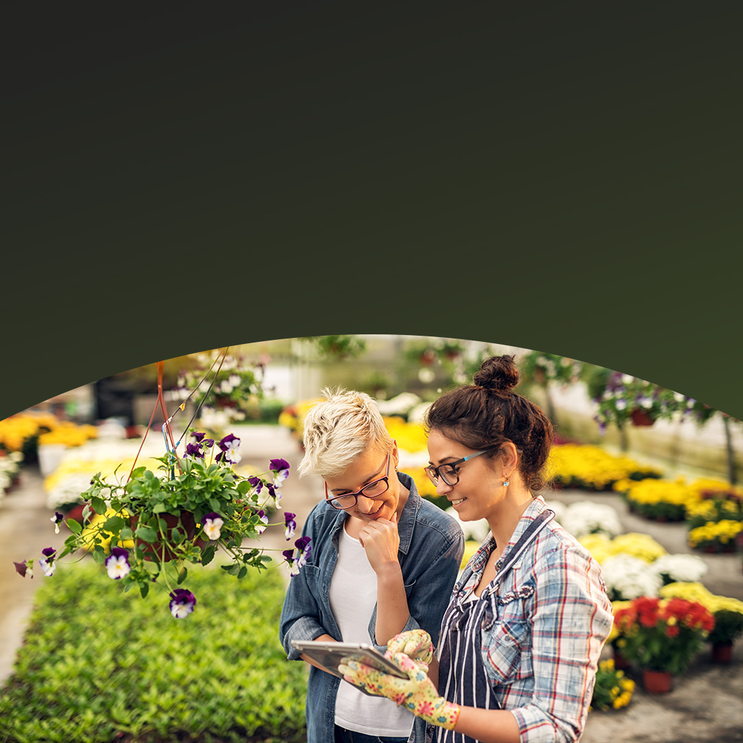 Small business owner of plant nursery helping customer.