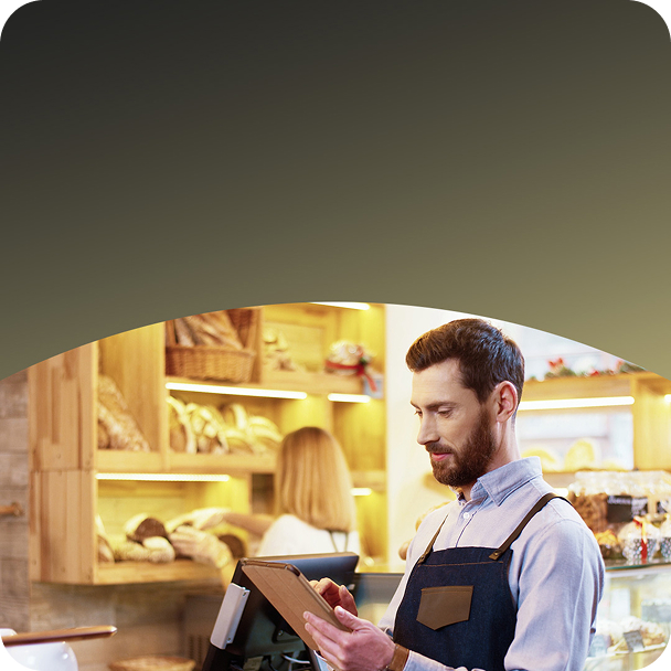 A man sitting at a restaurant table, focused on using a tablet for browsing or ordering food.