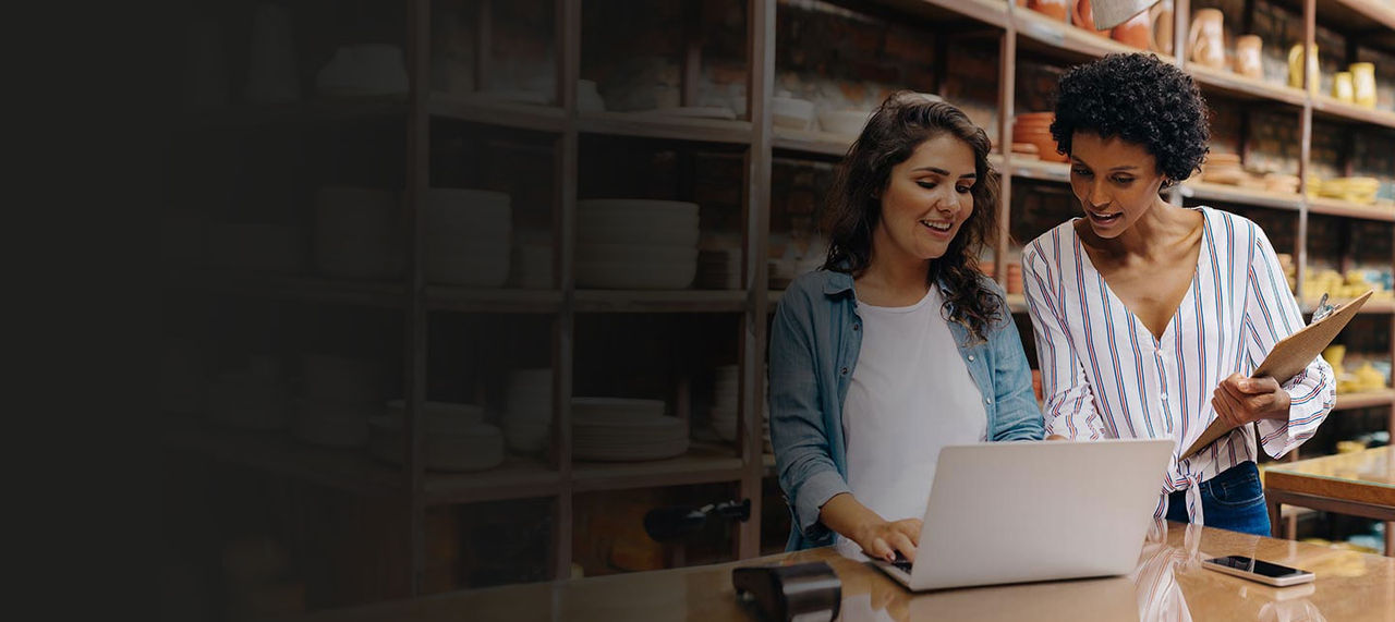 Two young shop owners using laptop in their pottery store.