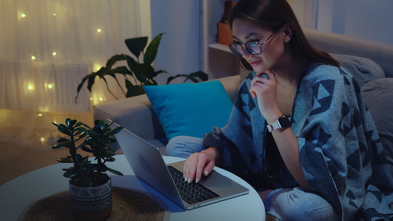Young woman working on a laptop at night.