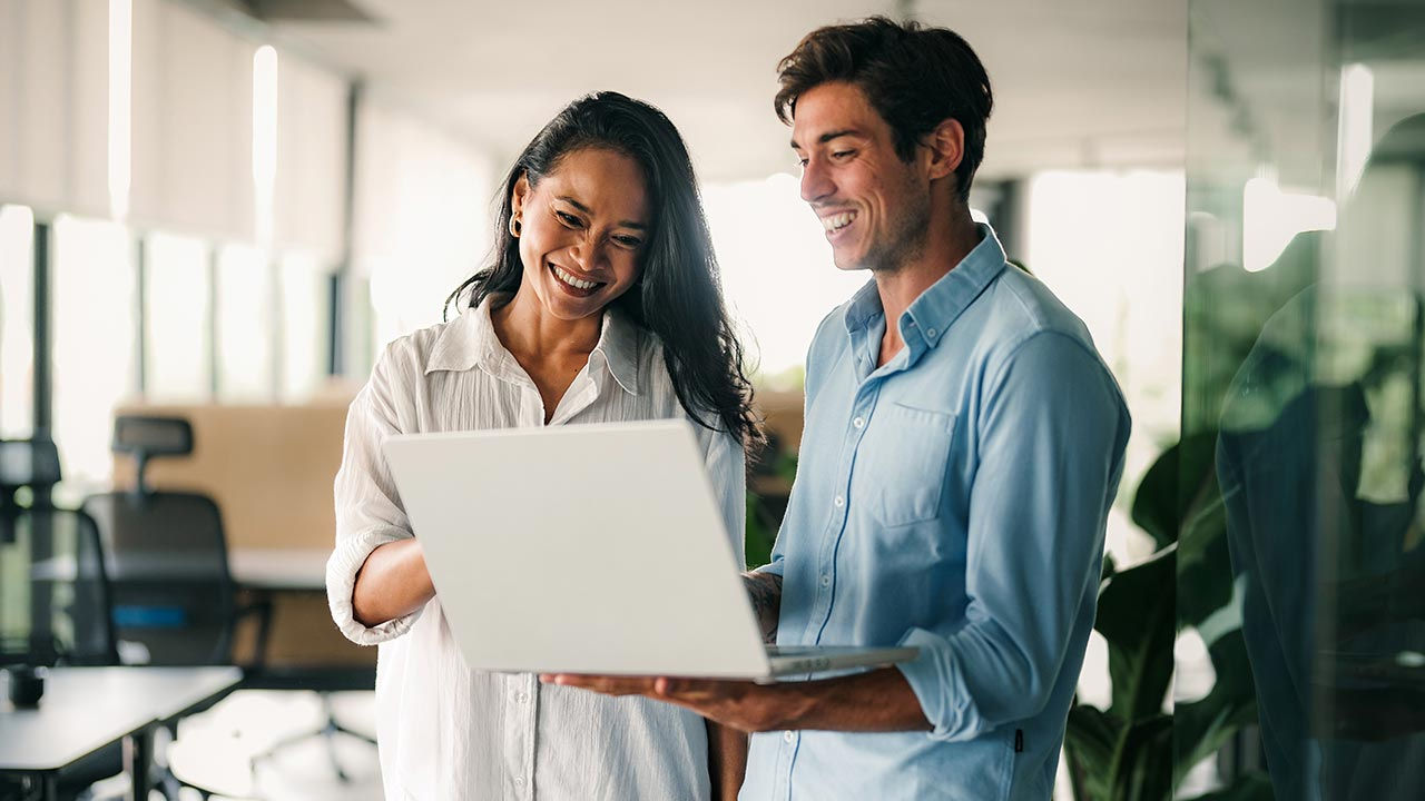 Two colleagues standing to review laptop.