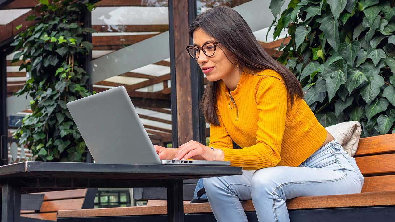 Woman using laptop on an outdoor patio.