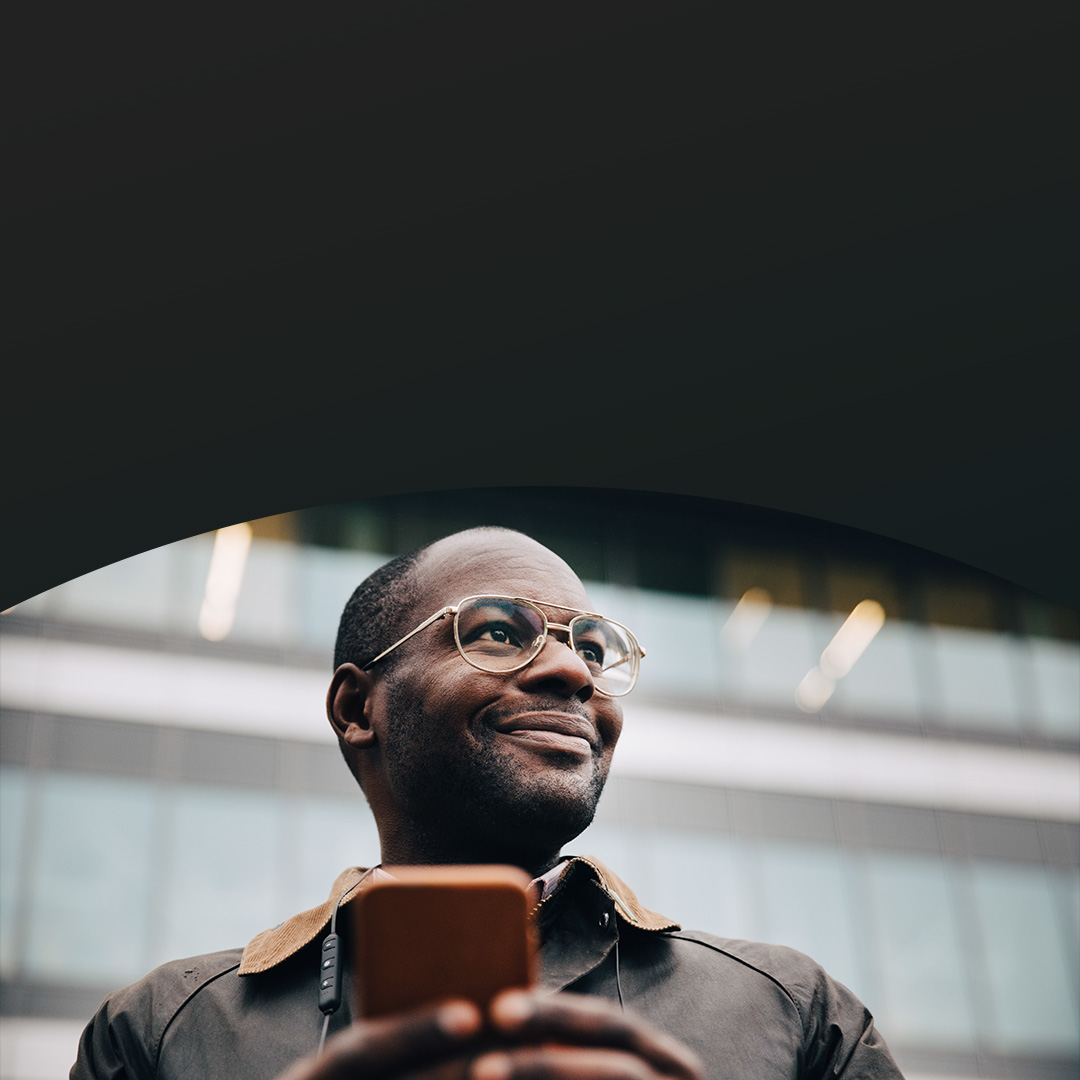Black man smiling looking away with phone in hand.