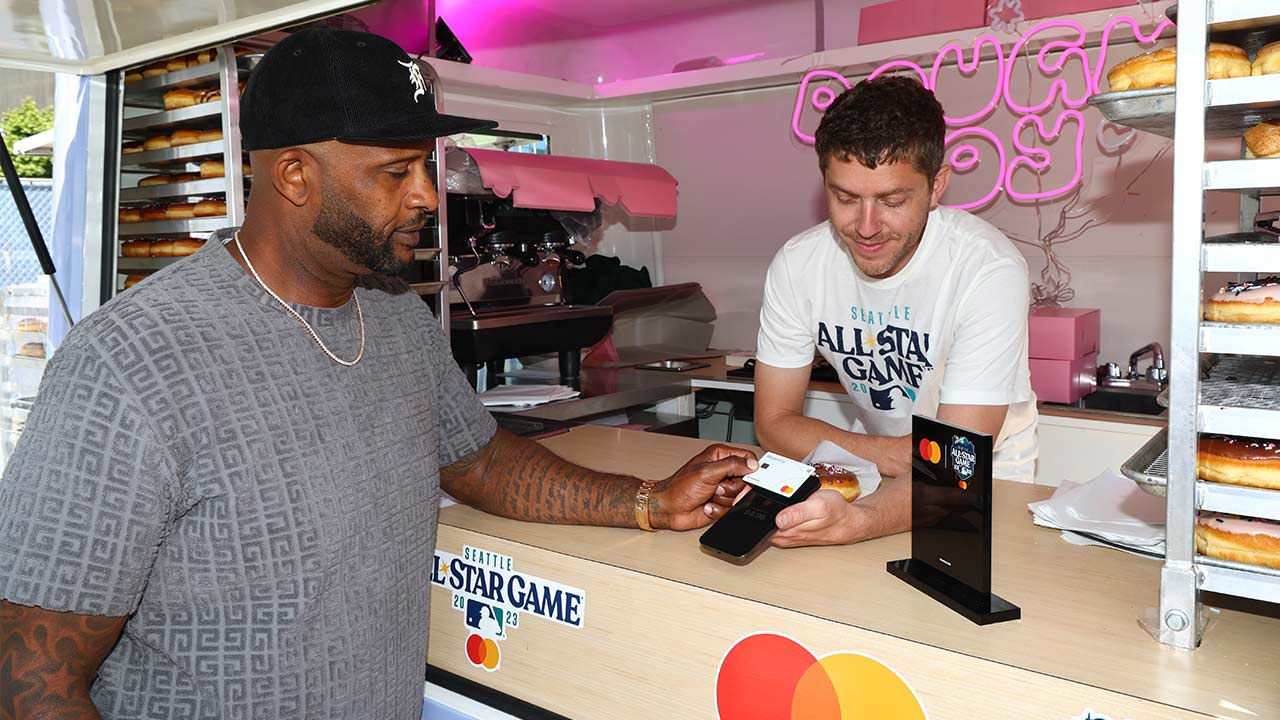 Man buying at point of sale by tapping credit card on an iphone.