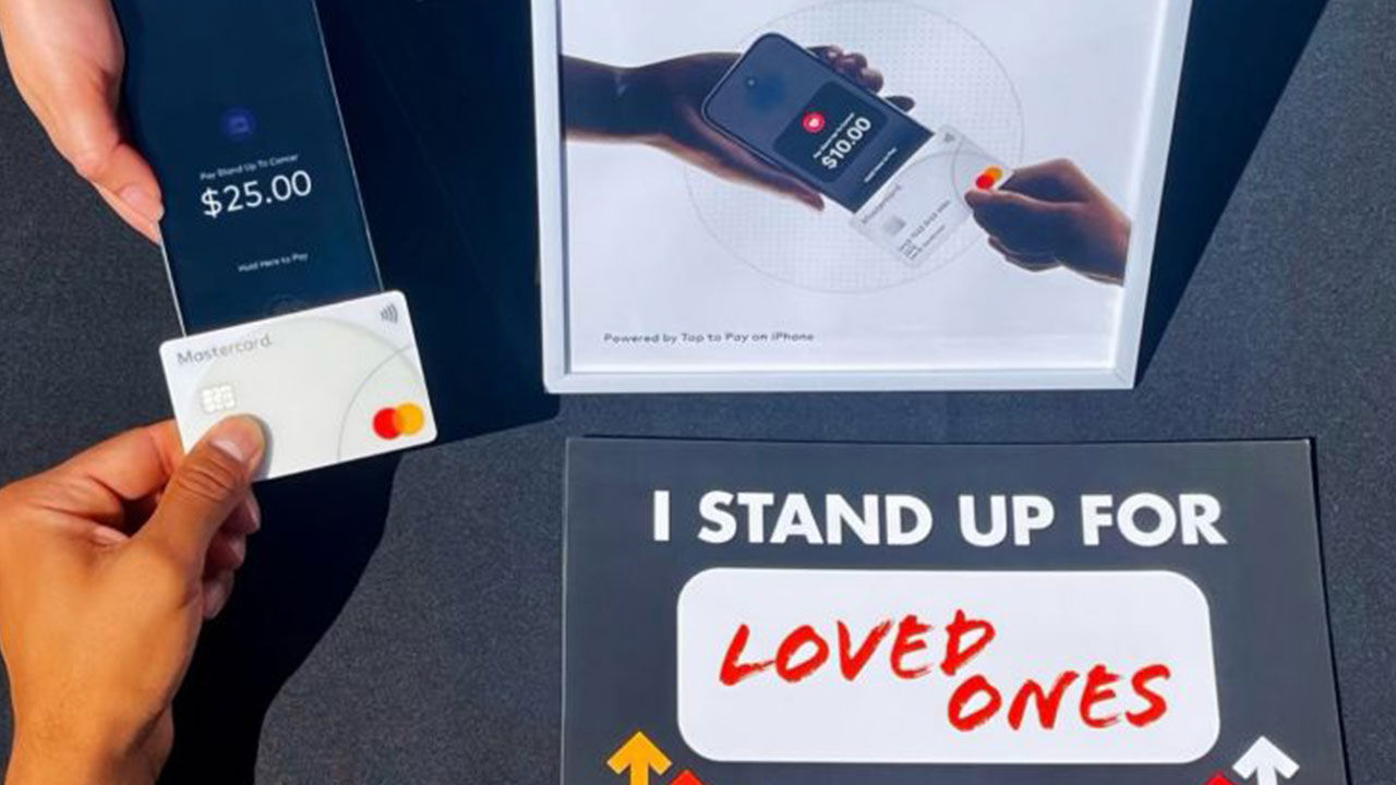 Person donating money to a cause by tapping credit card on an iphone.