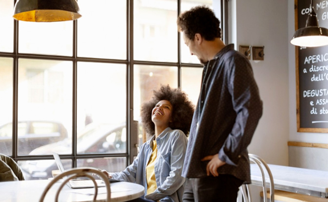 Happy male and female entrepreneurs looking at each other at cafe.