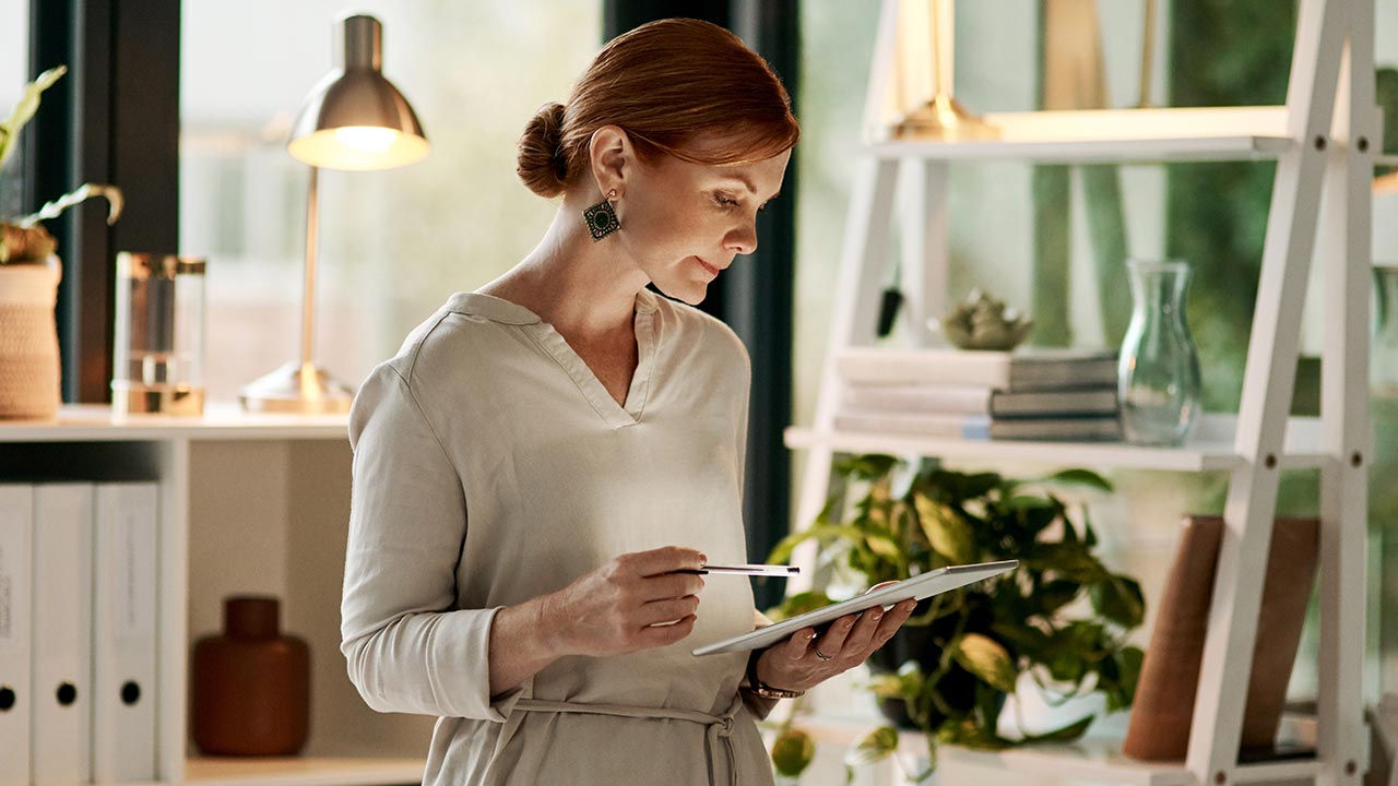 Small-business owner pouring over a tablet in home office.
