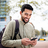 Young man using phone smiling.