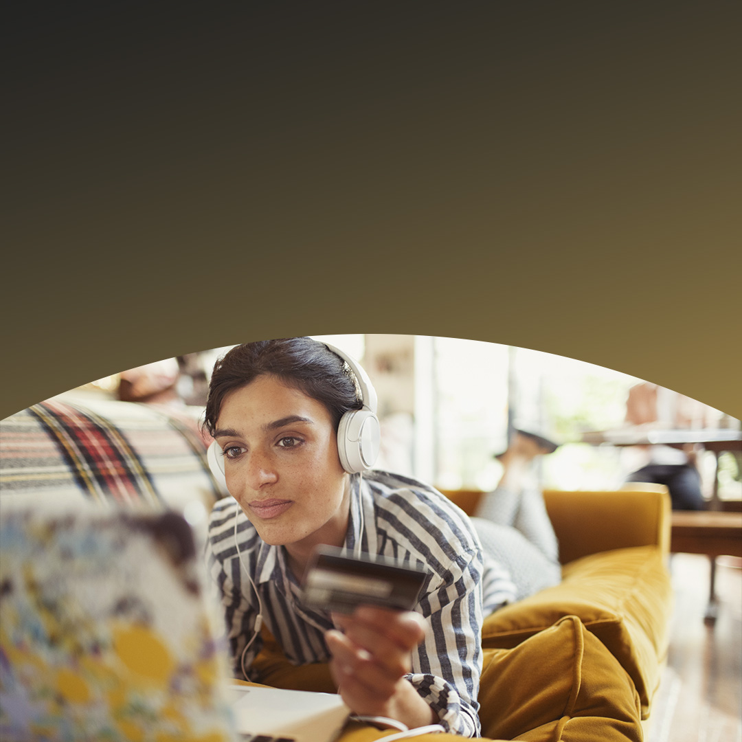 Young woman customer with credit card in hand wearing headphones