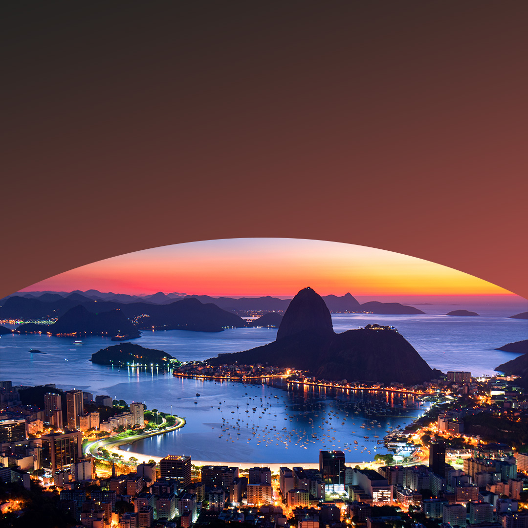 Nighttime view of a bay where the shoreline is lit by many small lights.