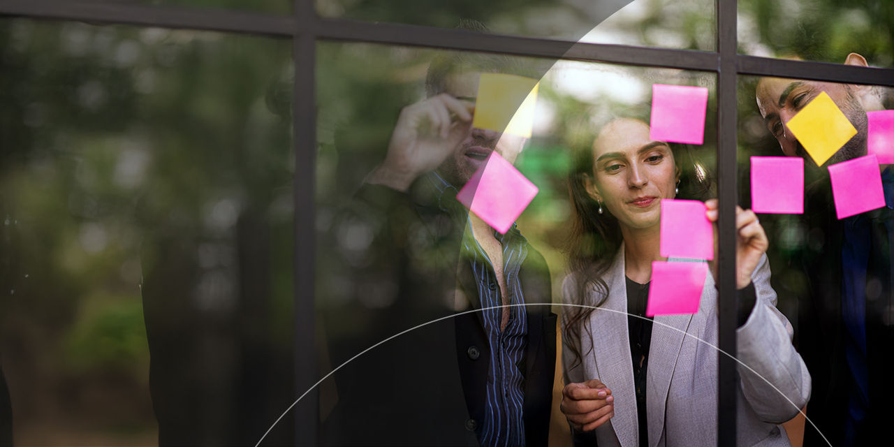 Man and woman placing post-it notes on a window.