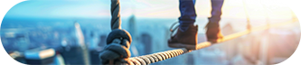 A person carefully walking on a tightrope above a city. 
