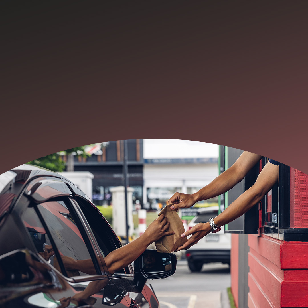 Hombre en auto recibiendo un pedido en el autoservicio.