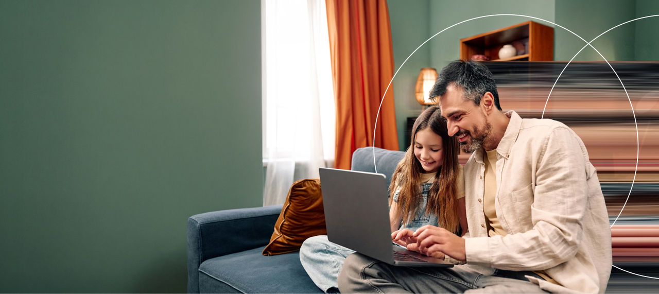 Padre e hija mirando una computadora portátil en el sofá