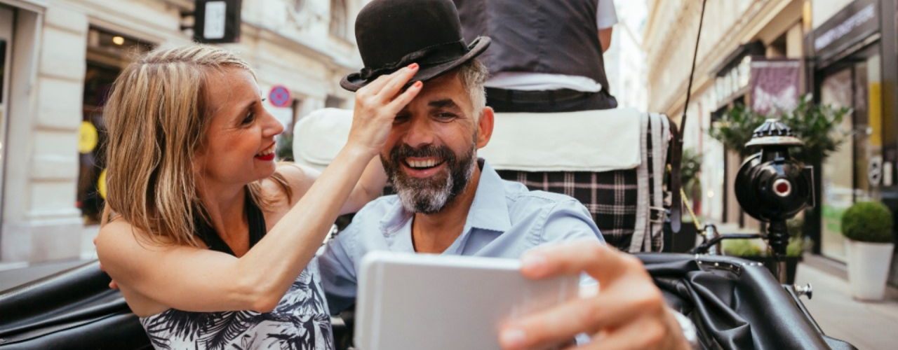 Una mujer coloca un sombrero hongo a su acompañante durante un paseo en carruaje tirado por caballos, ilustrando el impacto de la inflación en el gasto del consumidor y la perdurabilidad de la economía de la experiencia.