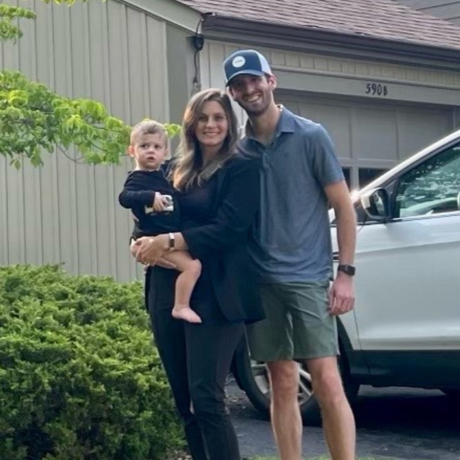 Family posing for picture in the driveway of their home.